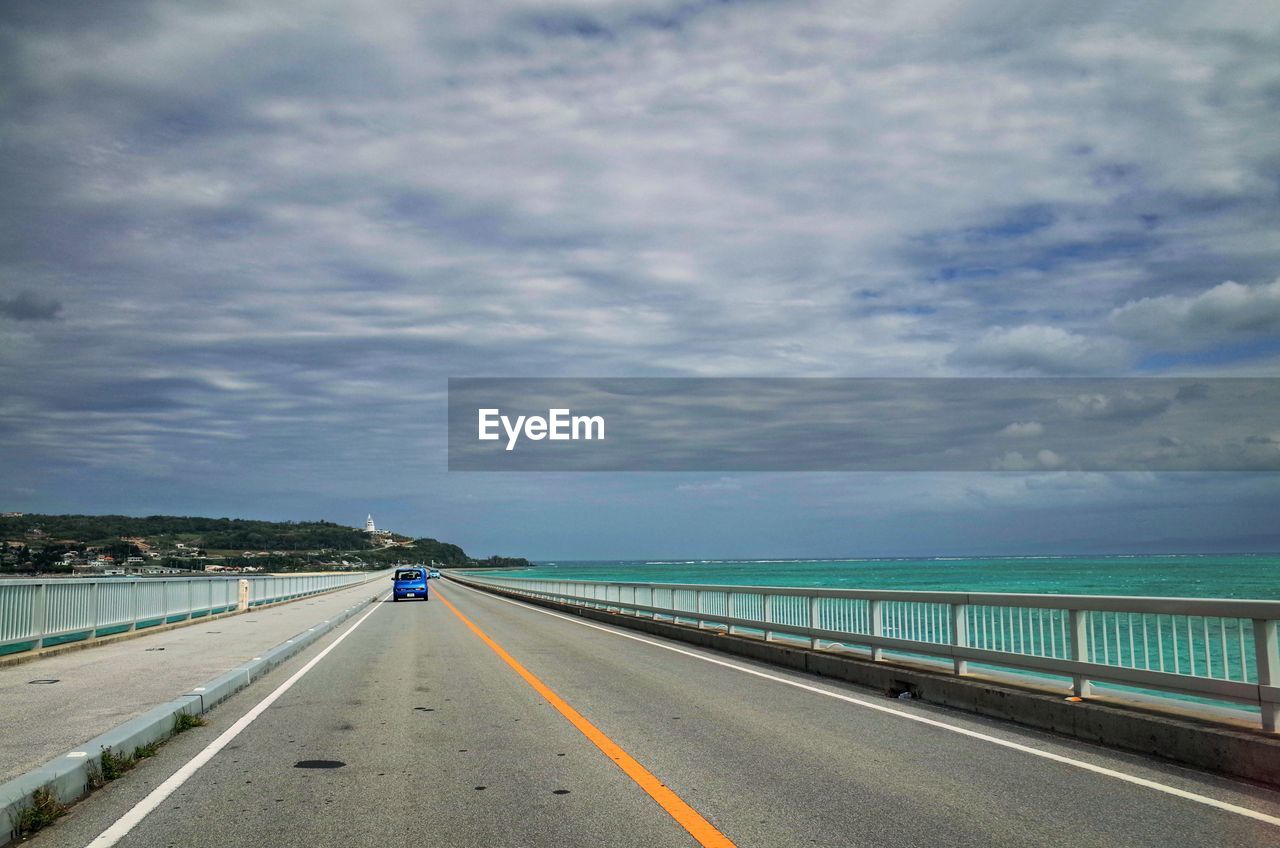 VIEW OF HIGHWAY AGAINST CLOUDY SKY