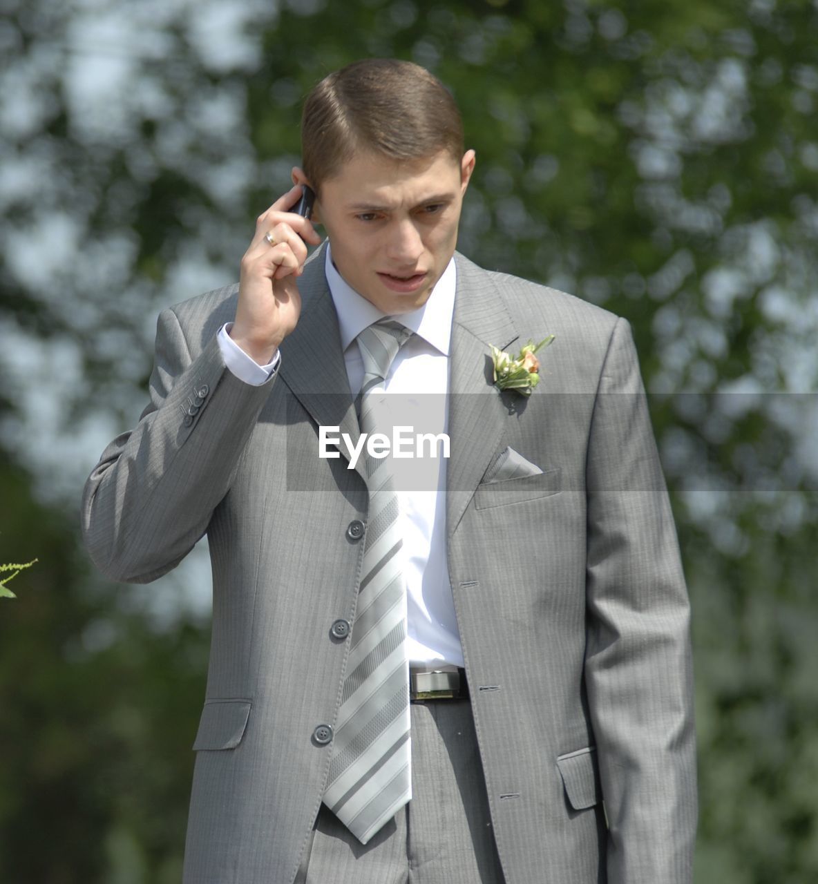 Bridegroom talking on mobile phone while standing outdoors