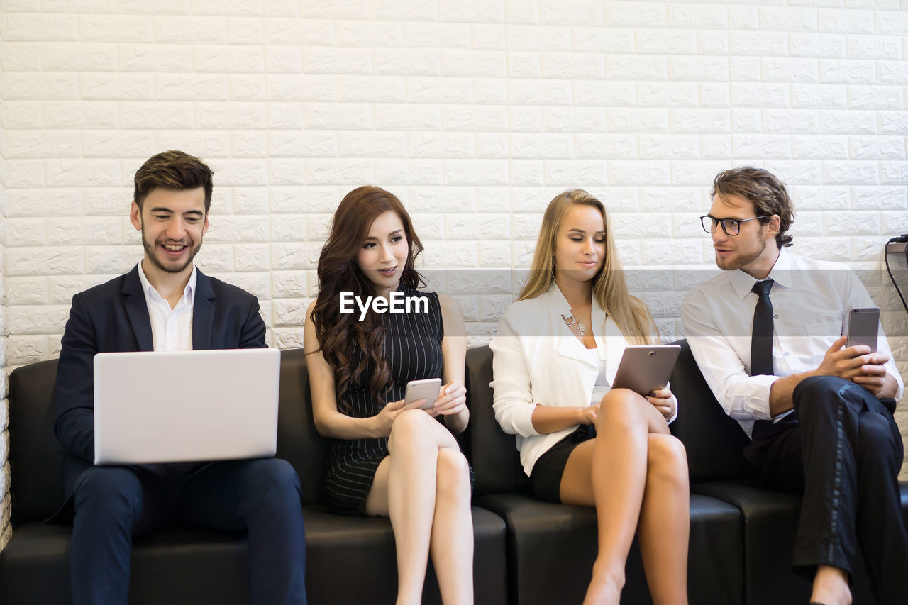 Business colleagues using technologies while sitting in office