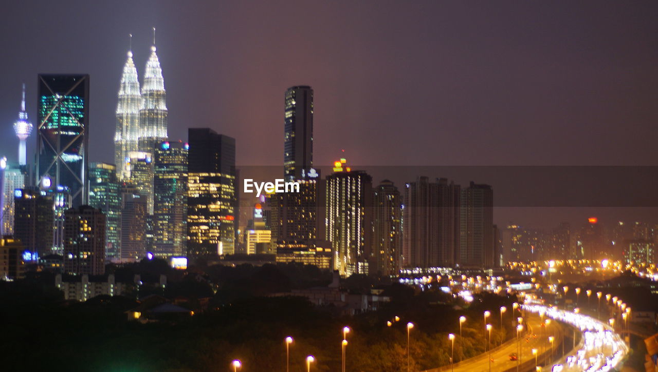 AERIAL VIEW OF ILLUMINATED BUILDINGS AGAINST SKY AT NIGHT