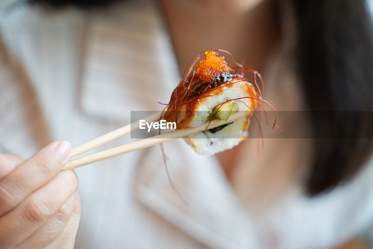 Hand hold unagi sushi roll.