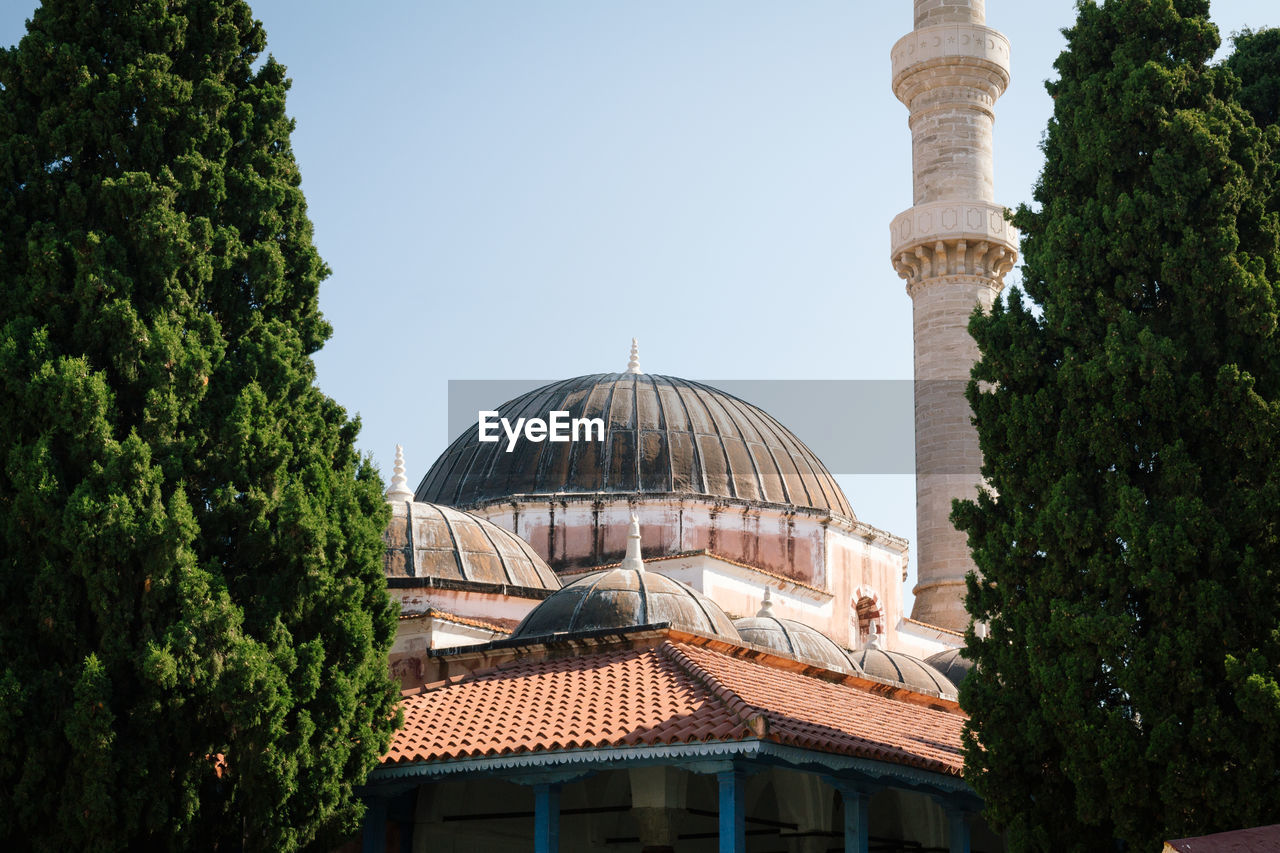 Low angle view of historical mosque building against sky between two trees