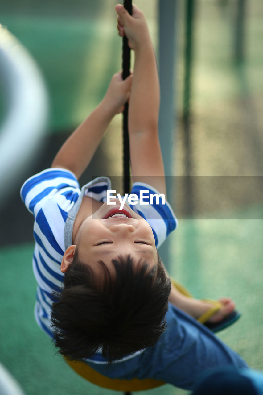 Happy boy swinging in playground