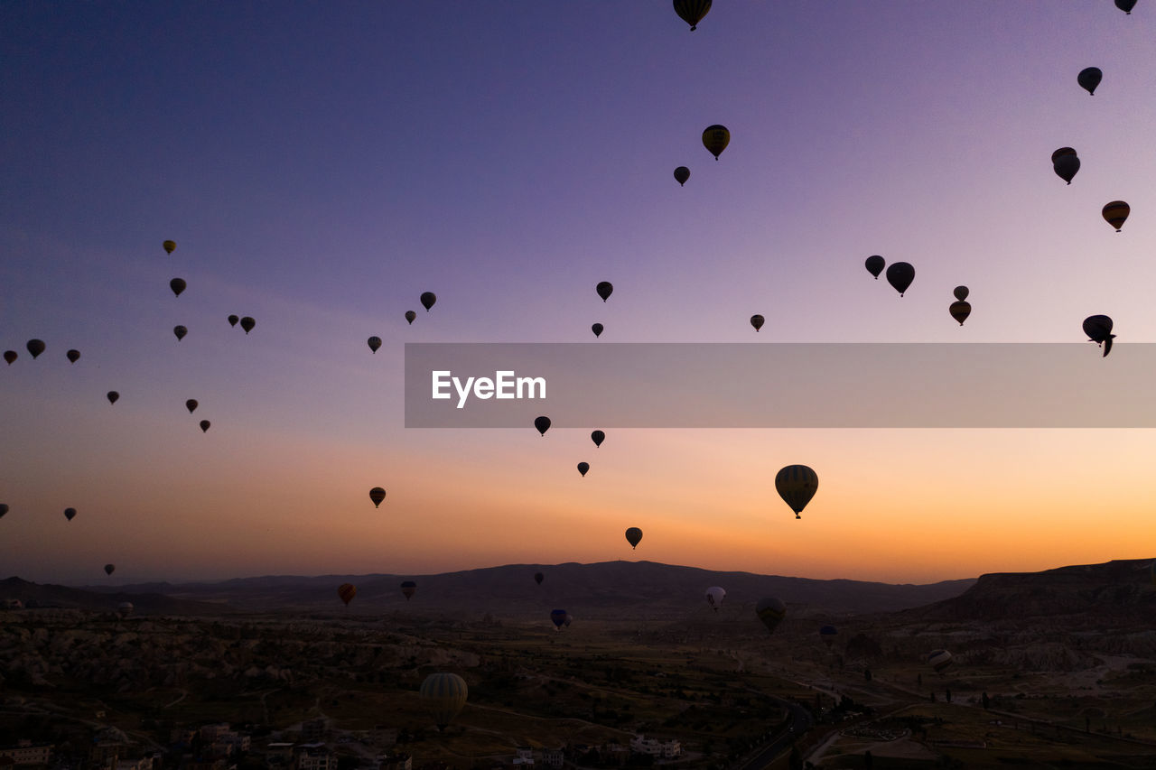 SILHOUETTE OF HOT AIR BALLOONS FLYING IN SKY AT SUNSET