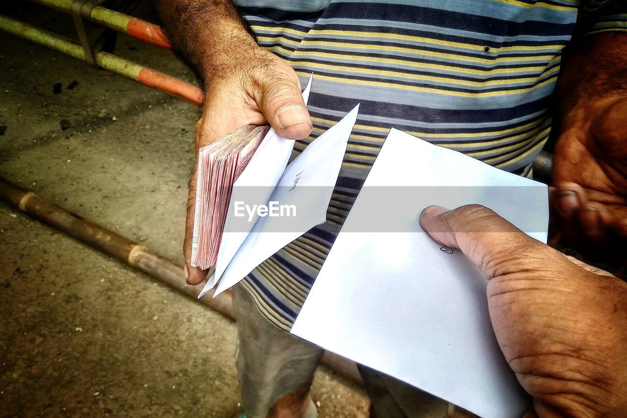 Cropped image of man giving envelope to friend