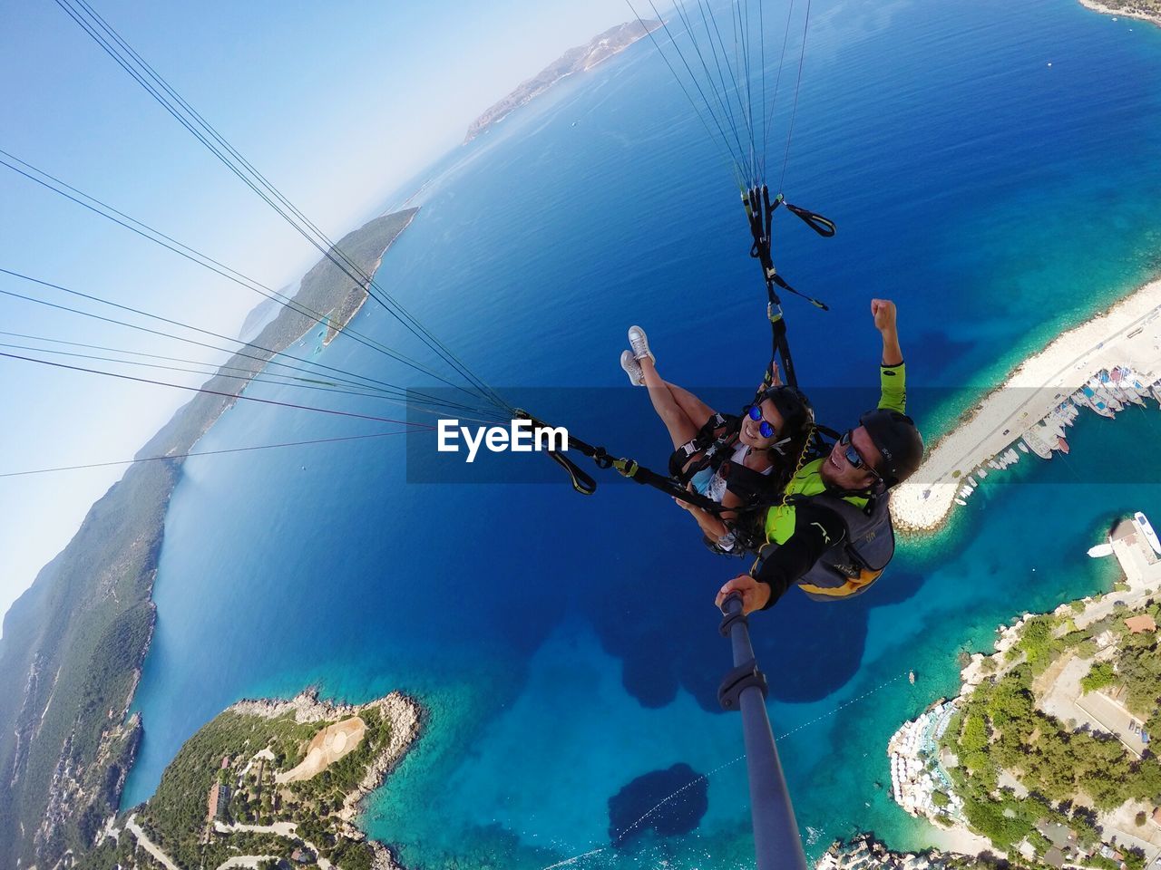 High angle view of couple paragliding over sea against sky