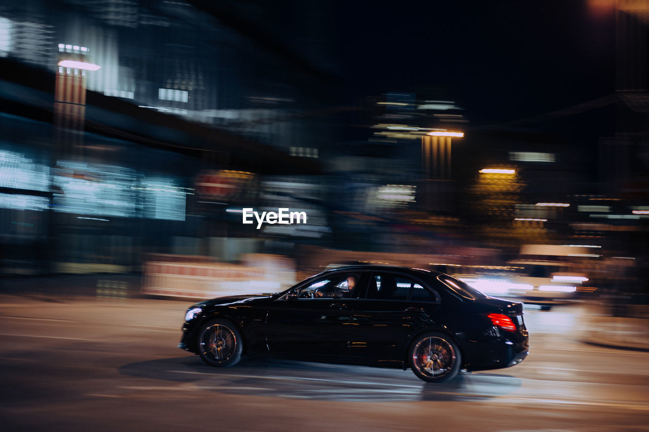 CAR ON ILLUMINATED CITY STREET AT NIGHT