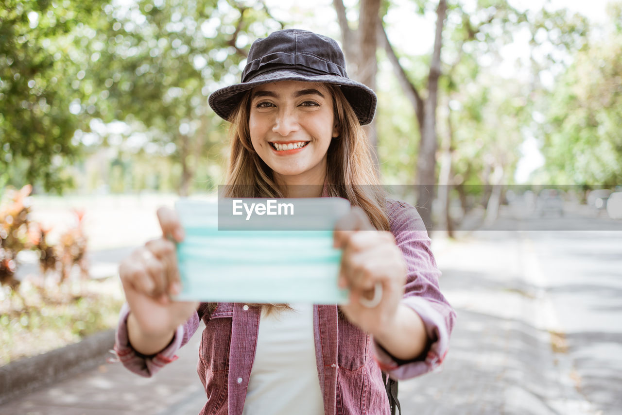 Portrait of smiling young woman holding smart phone