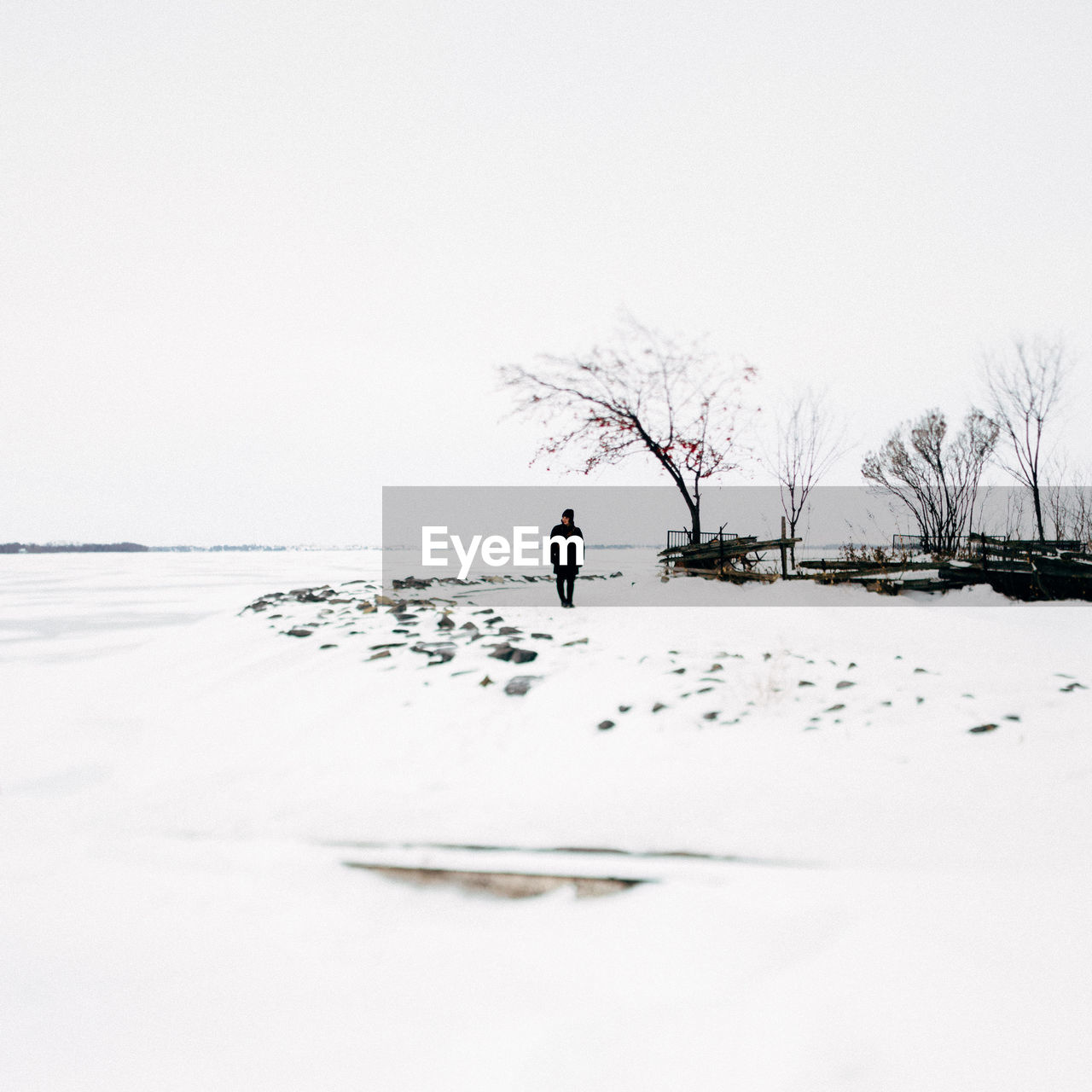 Person standing on frozen lake against sky