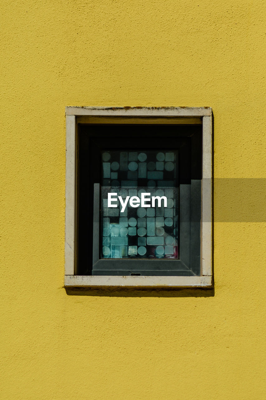 Close-up of window on yellow wall