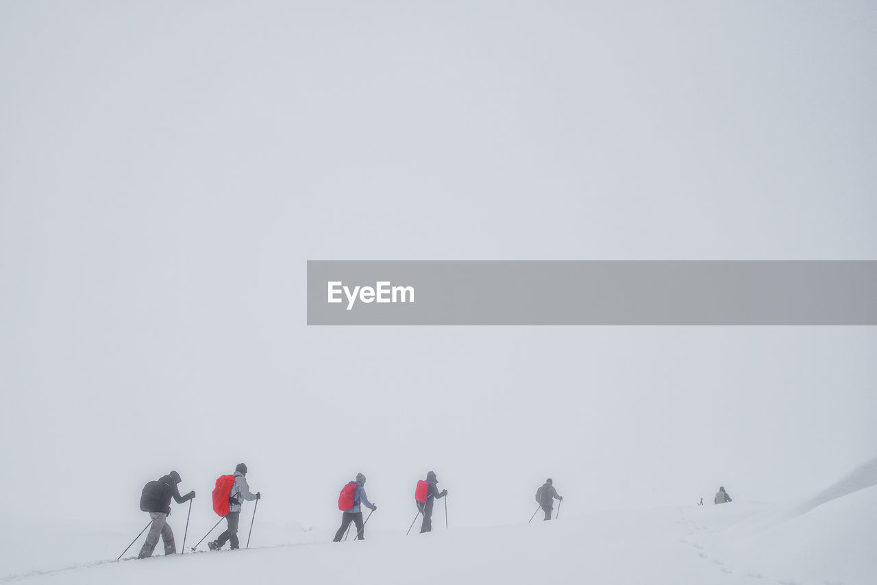 People walking on snow covered mountain during extreme weather