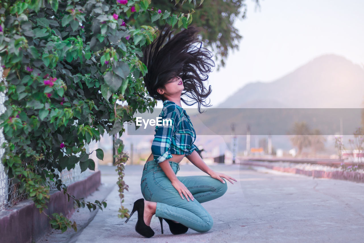 Teenage girl with tousled hair on roadside by plants