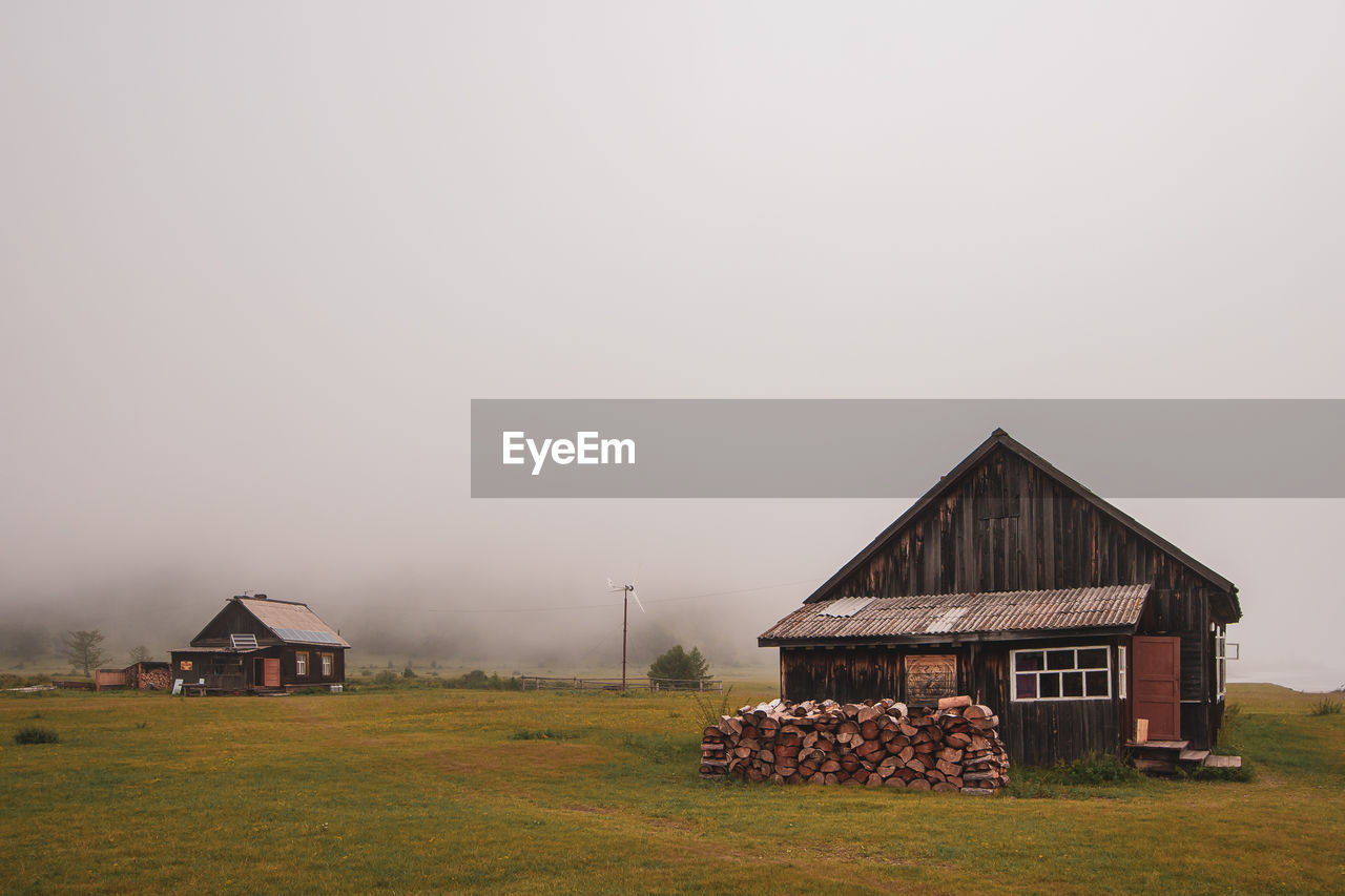 BARN ON FIELD BY HOUSE AGAINST SKY