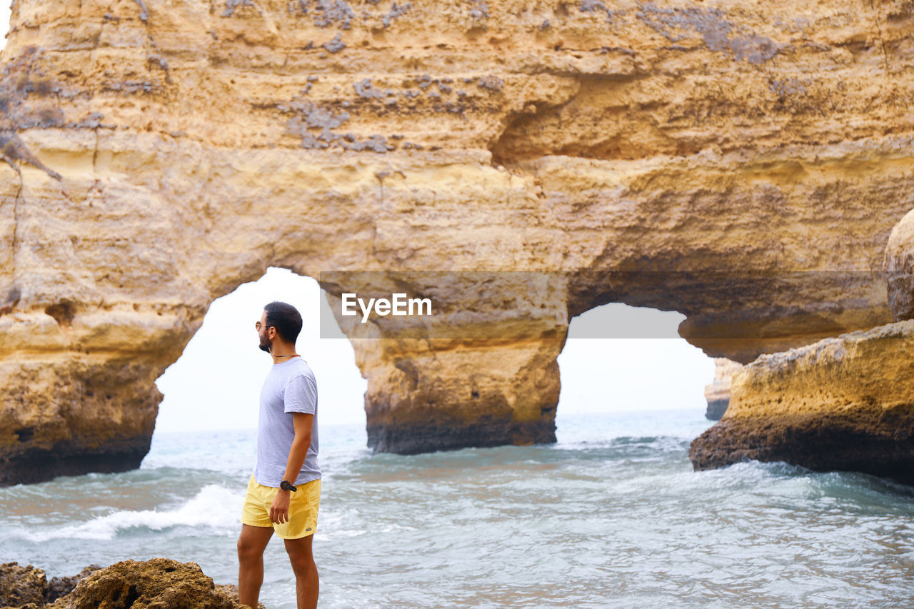 Full length of man standing on rock at beach