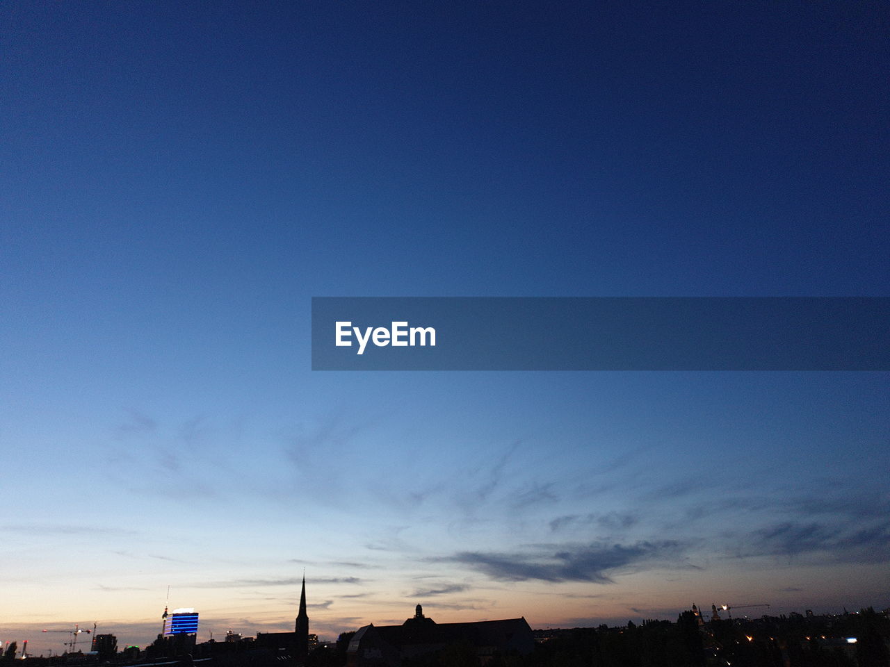 LOW ANGLE VIEW OF ILLUMINATED BUILDINGS AGAINST SKY AT SUNSET