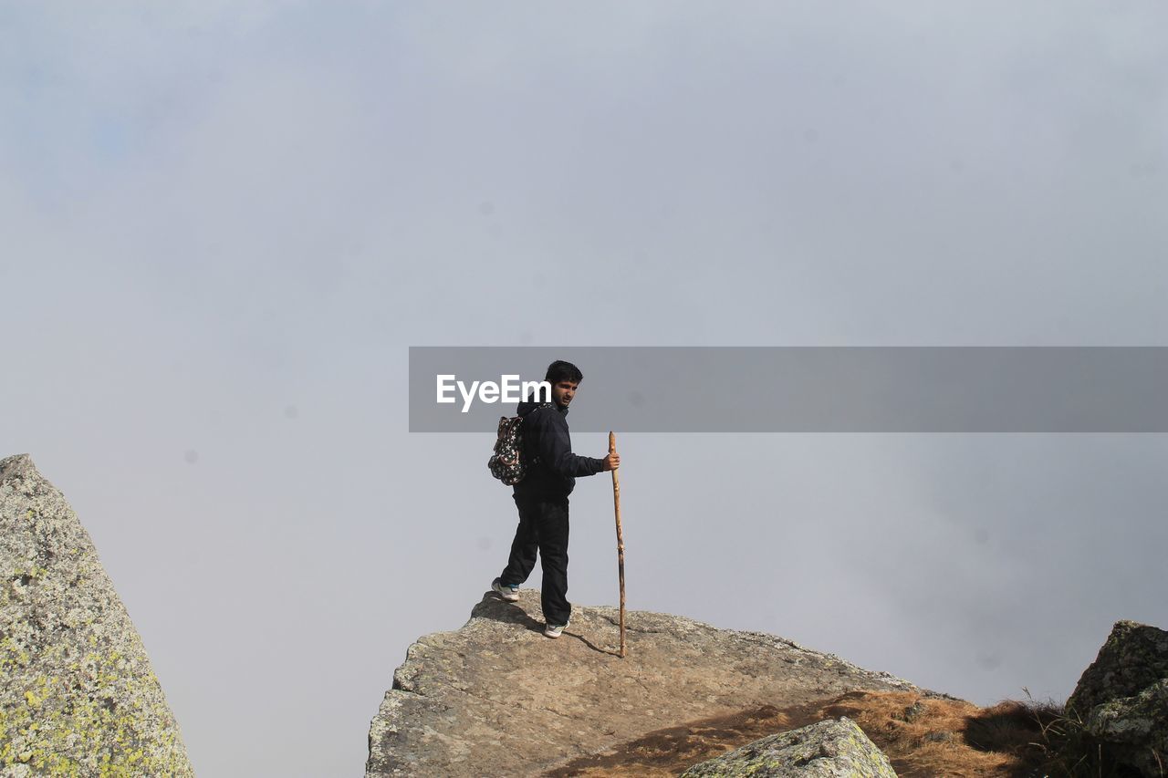 Full length of man standing on rock against clear sky