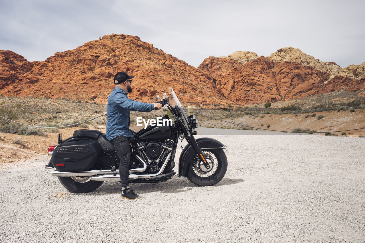 Man sitting on motorcycle at valley of fire state park, nevada, usa