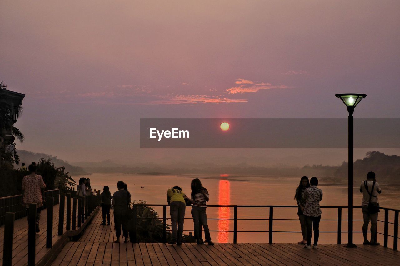 People on promenade against sky during sunset