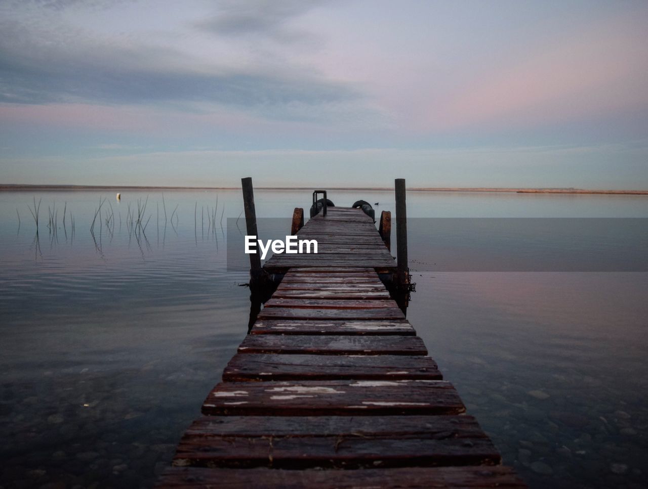 Pier over sea against sky during sunset