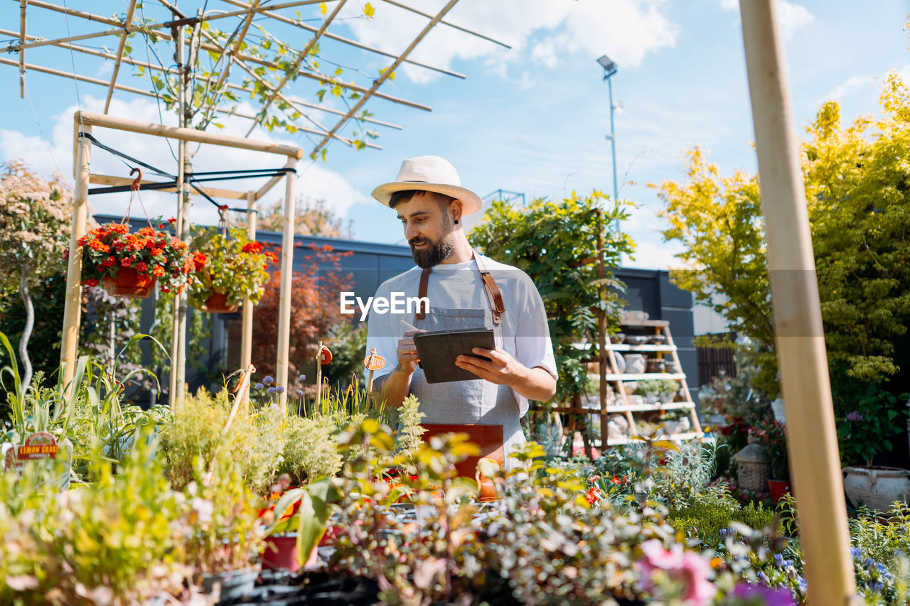 Man worker in garden centre. using tablet. gardener