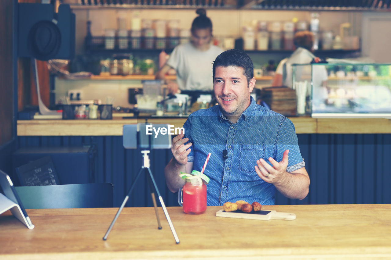 Social media influencer creating marketing content by filming video inside small restaurant