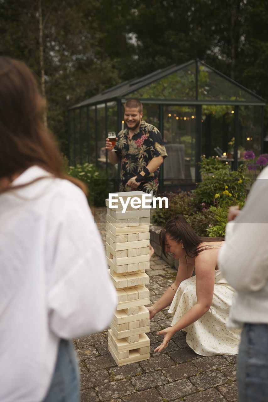 Friends playing giant jenga in garden