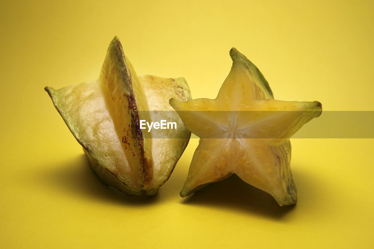 Close-up of halved starfruits against yellow background