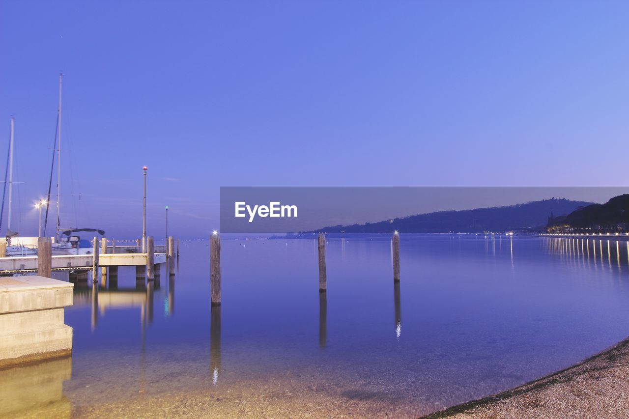 WOODEN POSTS IN LAKE AGAINST CLEAR SKY