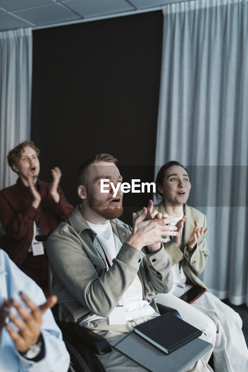 Male entrepreneur with disability applauding while sitting in seminar