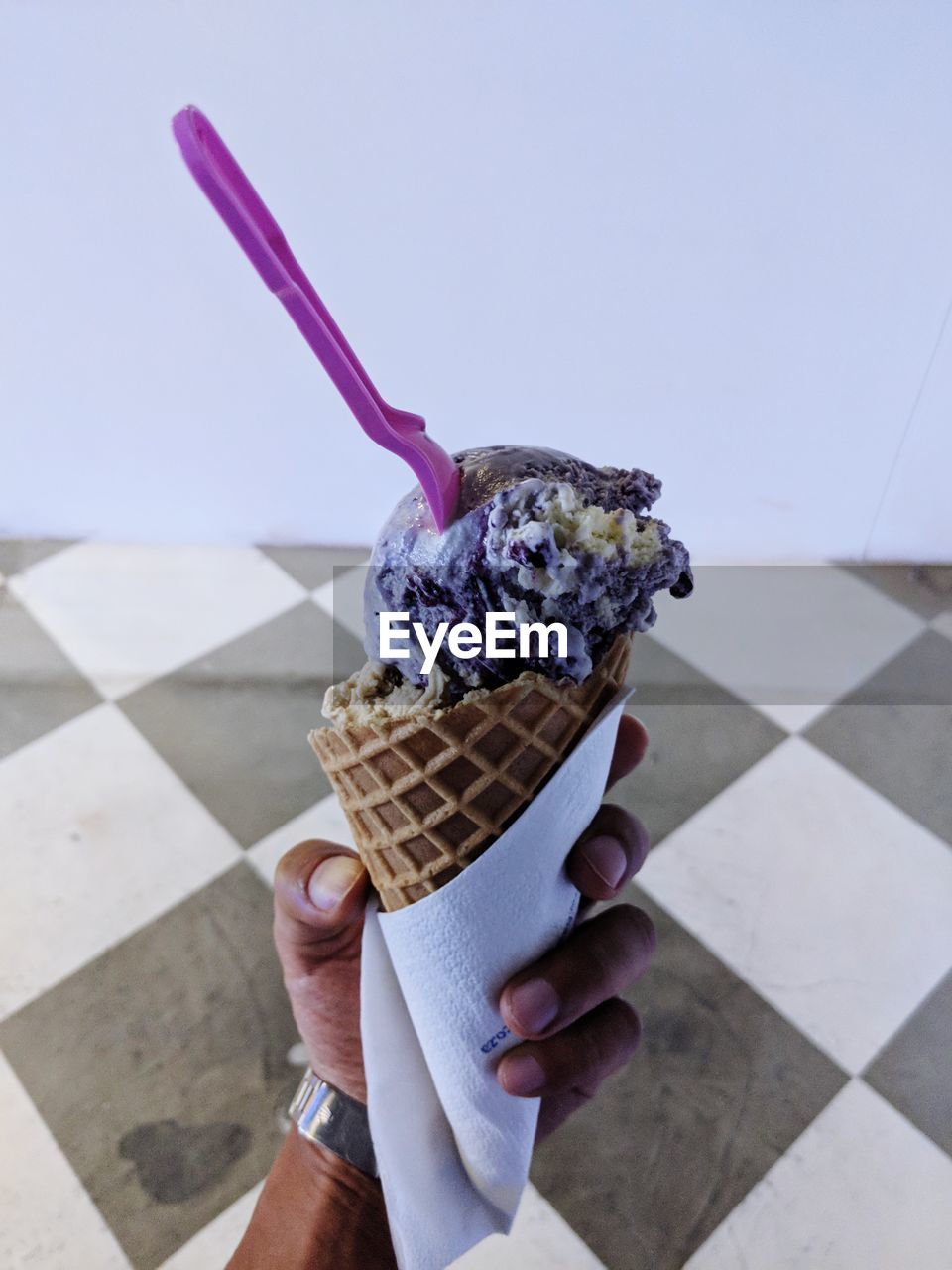 Cropped hand of person holding ice cream cone at home