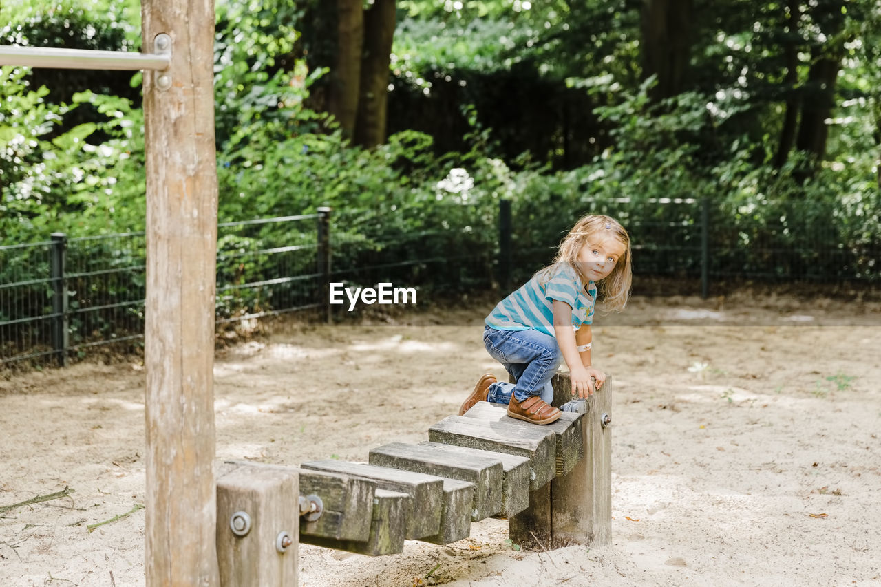 Full length of girl standing on outdoor play equipment in park