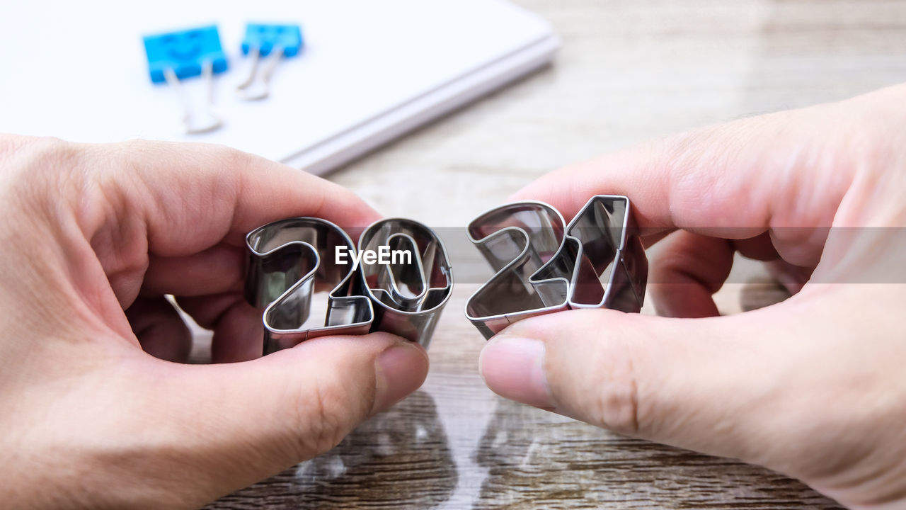 Cropped hand of person holding metallic numbers at table