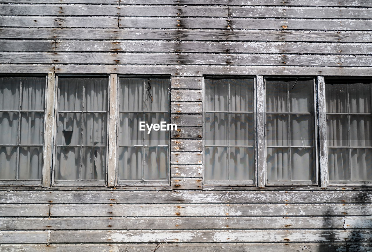 Windows of abandoned and weathered wood house