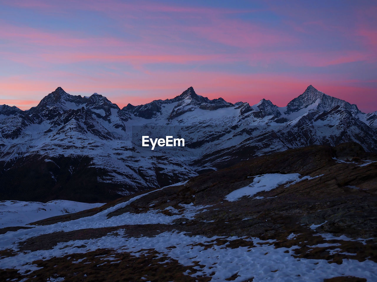 Scenic view of snow mountains against sky at sunset