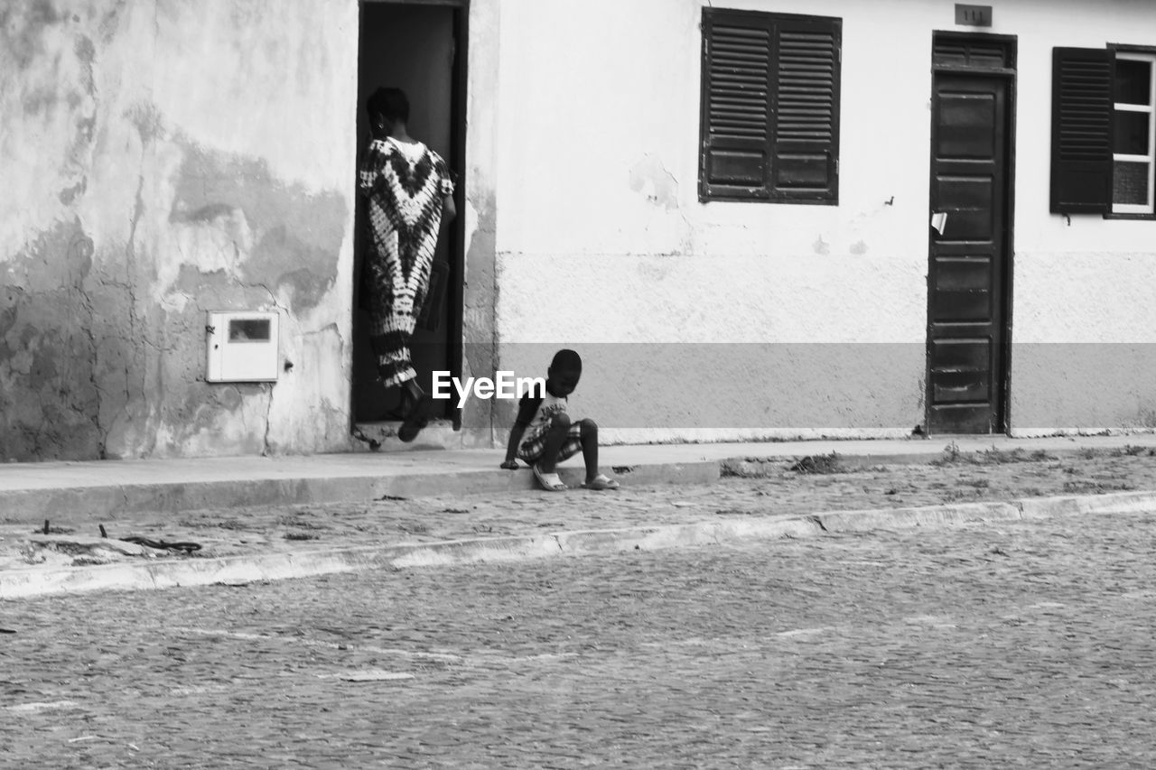 BOY ON HOUSE AGAINST WALL