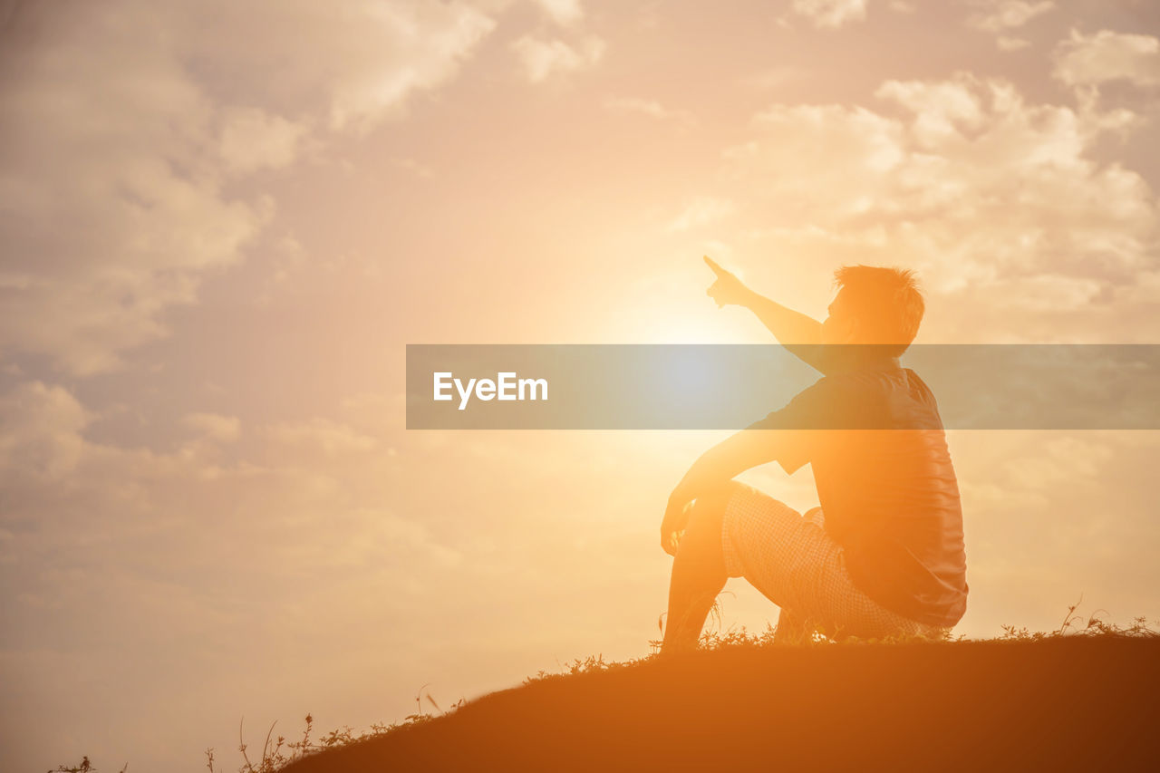 Silhouette man sitting against sky during sunset