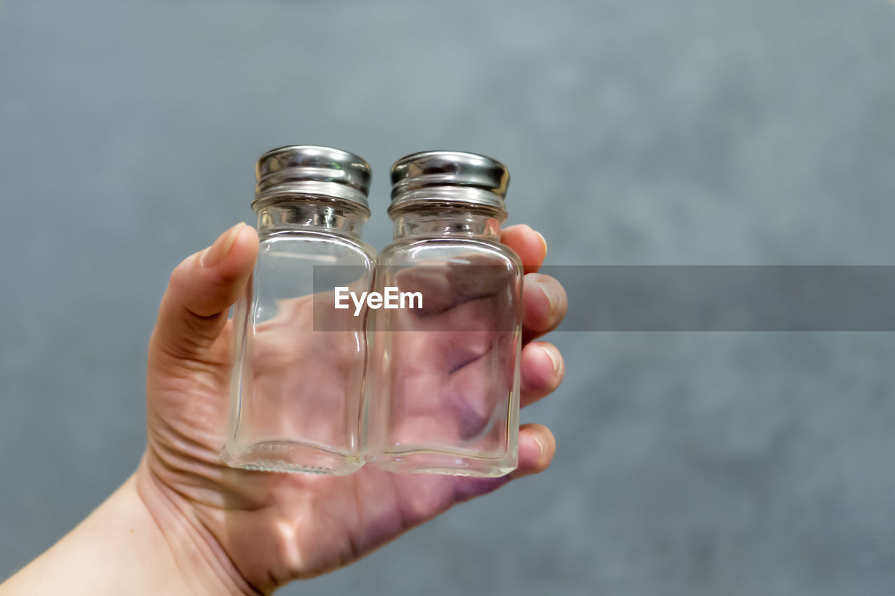 Close-up of hand holding empty glass bottles
