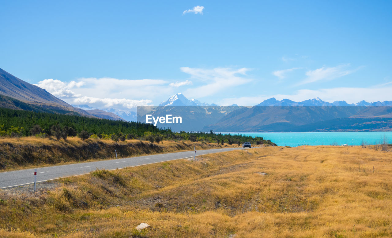 Scenic view of road by mountains against sky