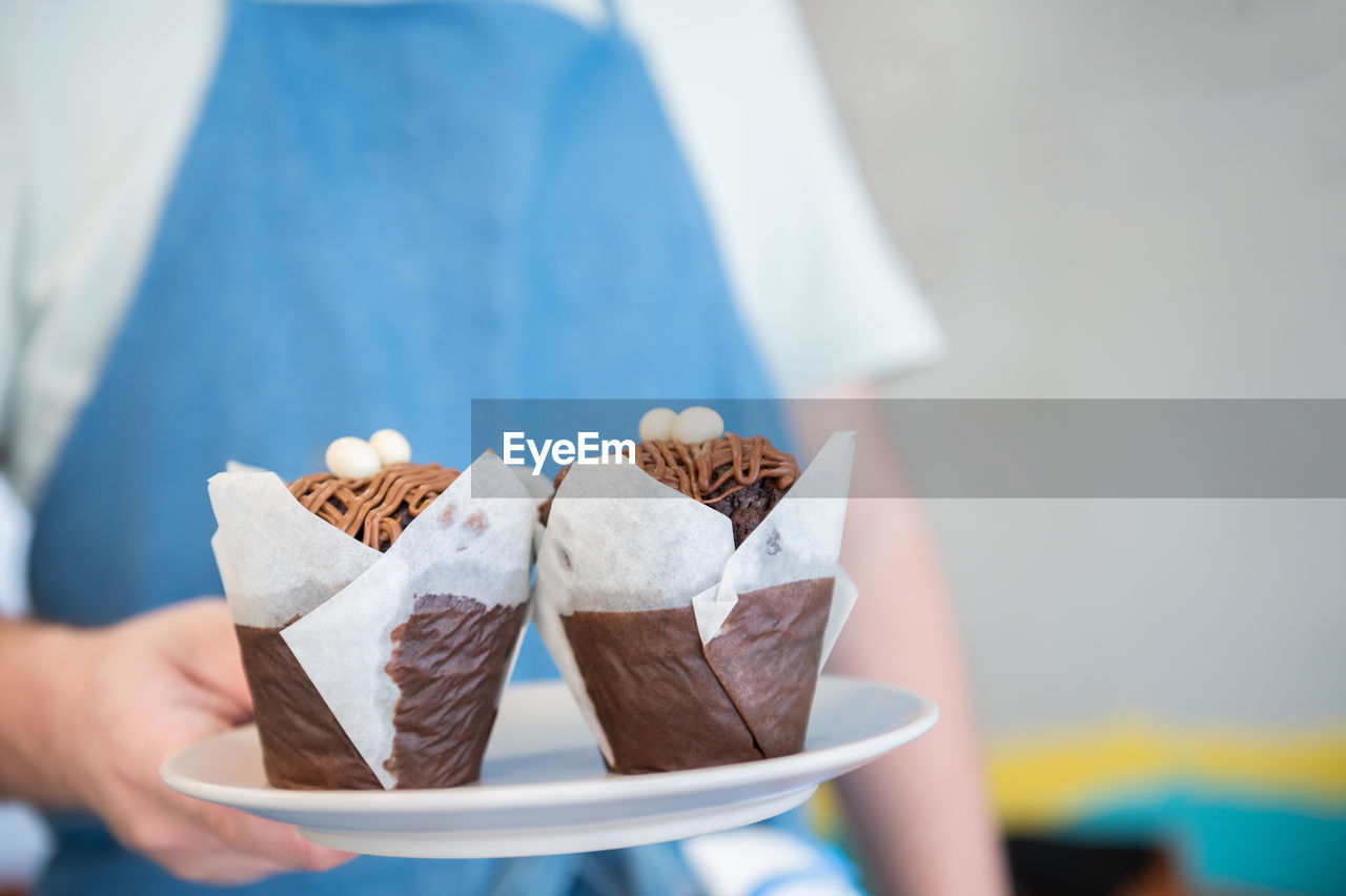 CLOSE-UP OF HAND HOLDING CHOCOLATE CAKE