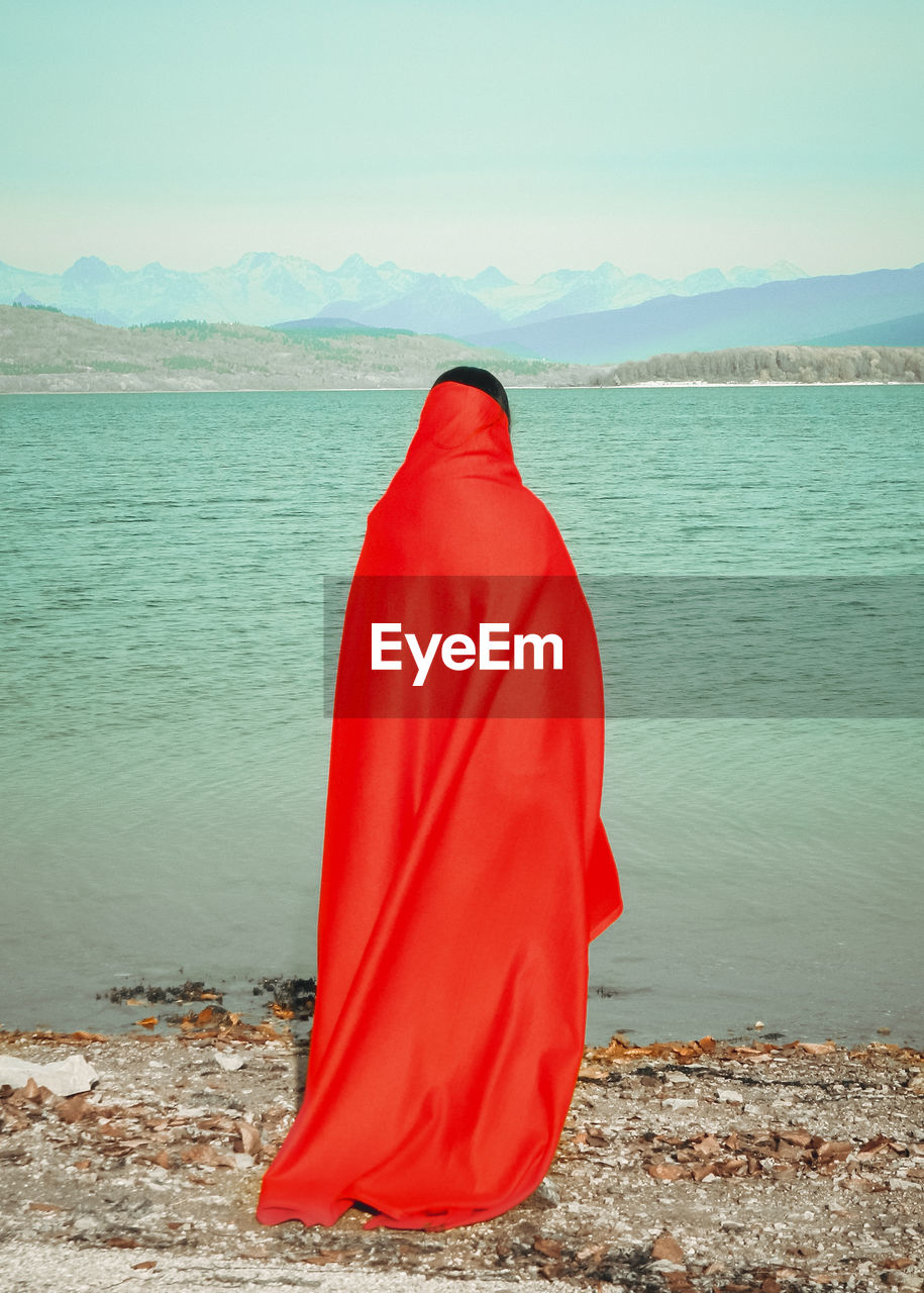 Rear view of woman on beach against sky