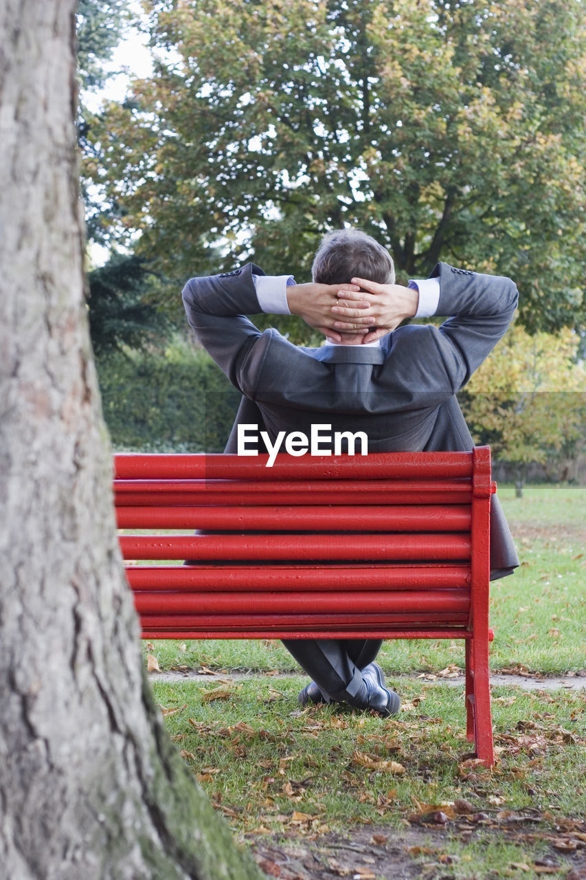 Businessman relaxing on a red park bench