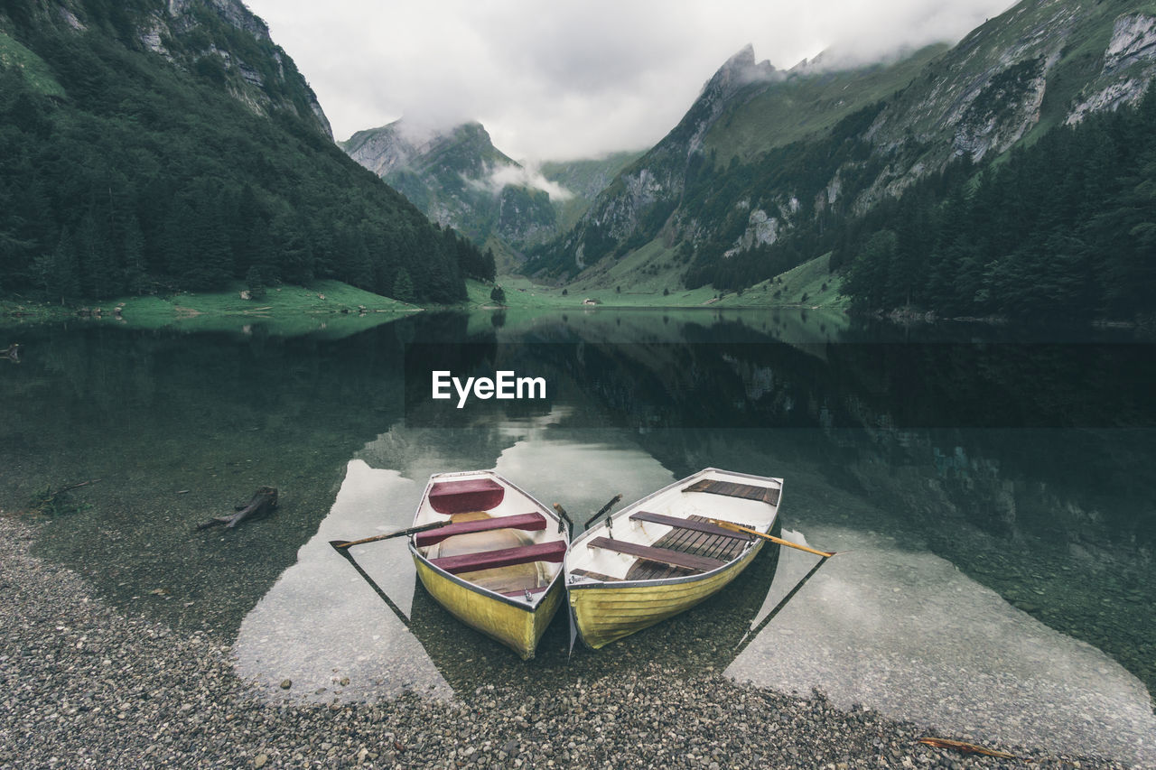 Boats at lakeshore against mountains