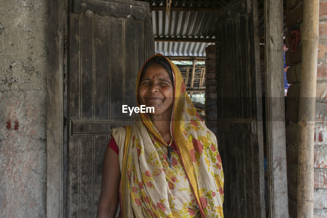 Happy indian woman in saree standing in front of door
