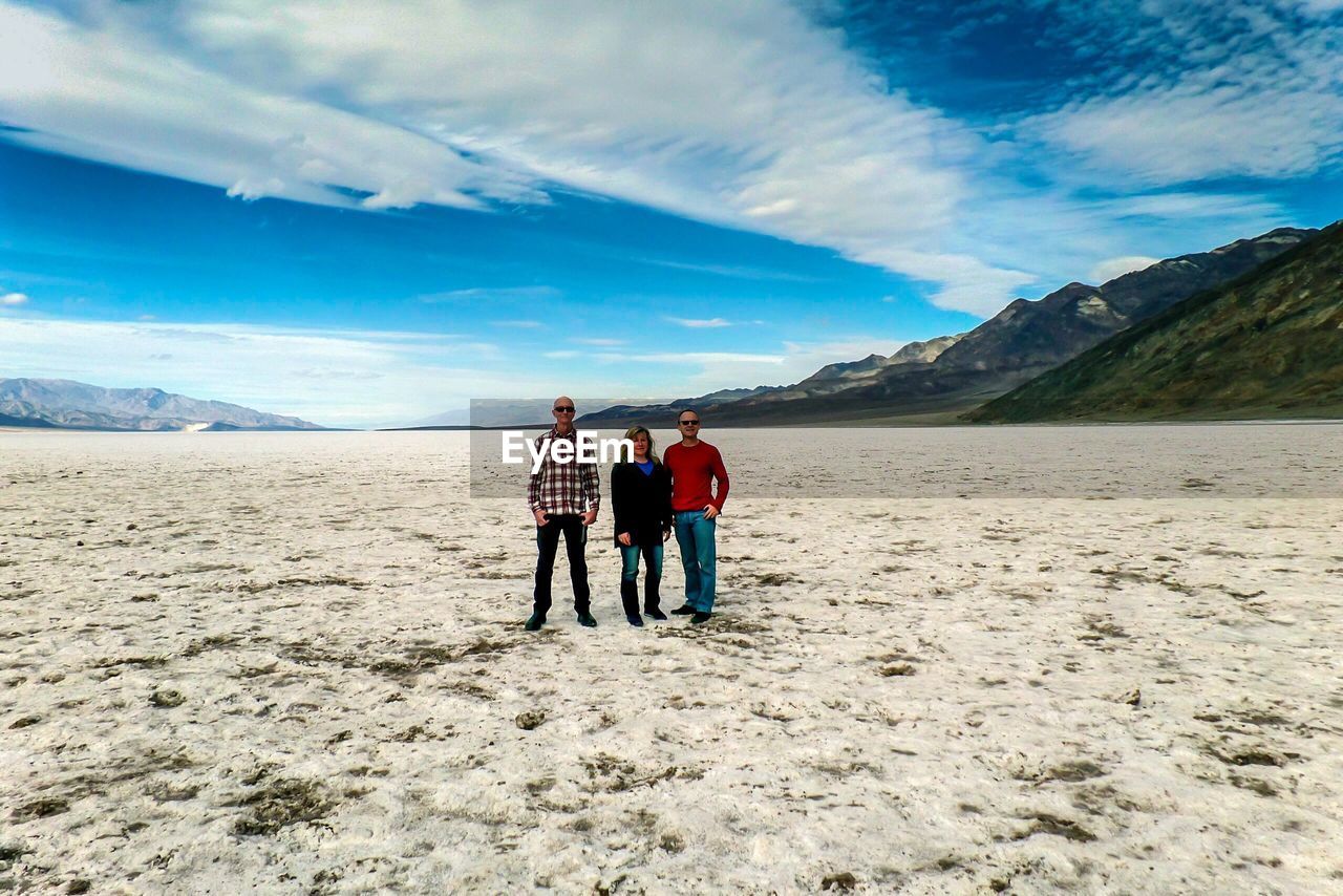 Full length of friends standing on desert against sky