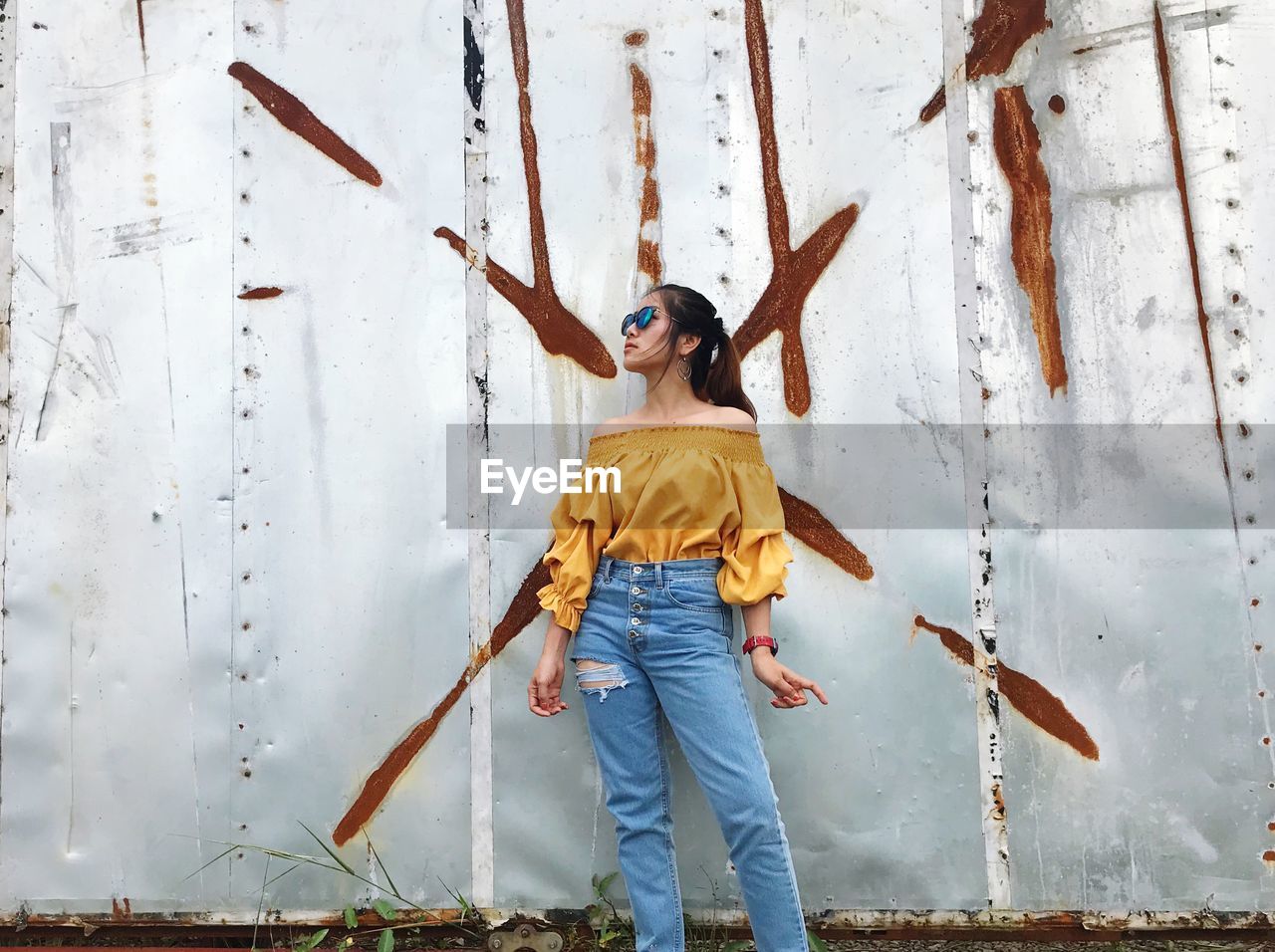 Fashionable woman looking away while standing against metallic wall