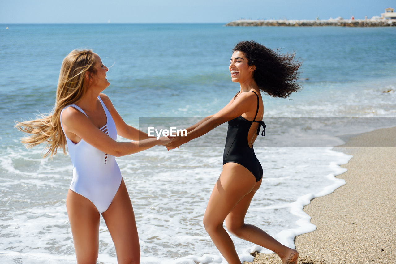 Happy female friends on shore at beach