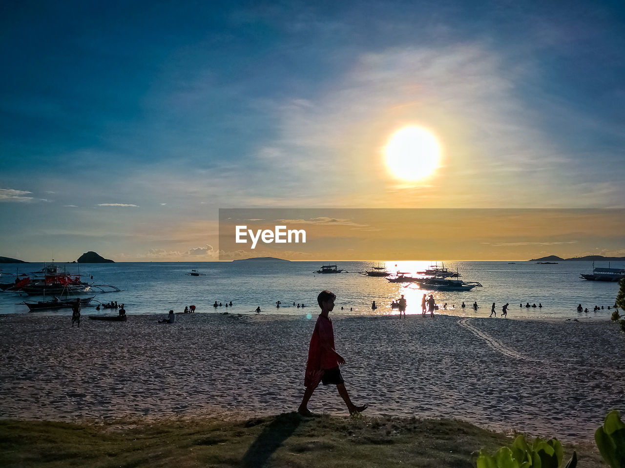 WOMAN STANDING ON BEACH DURING SUNSET