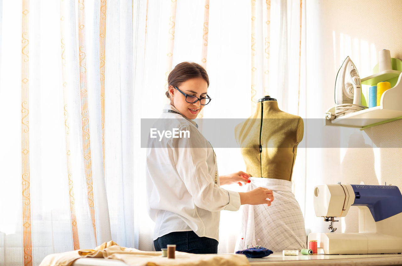 Young woman standing by table at home