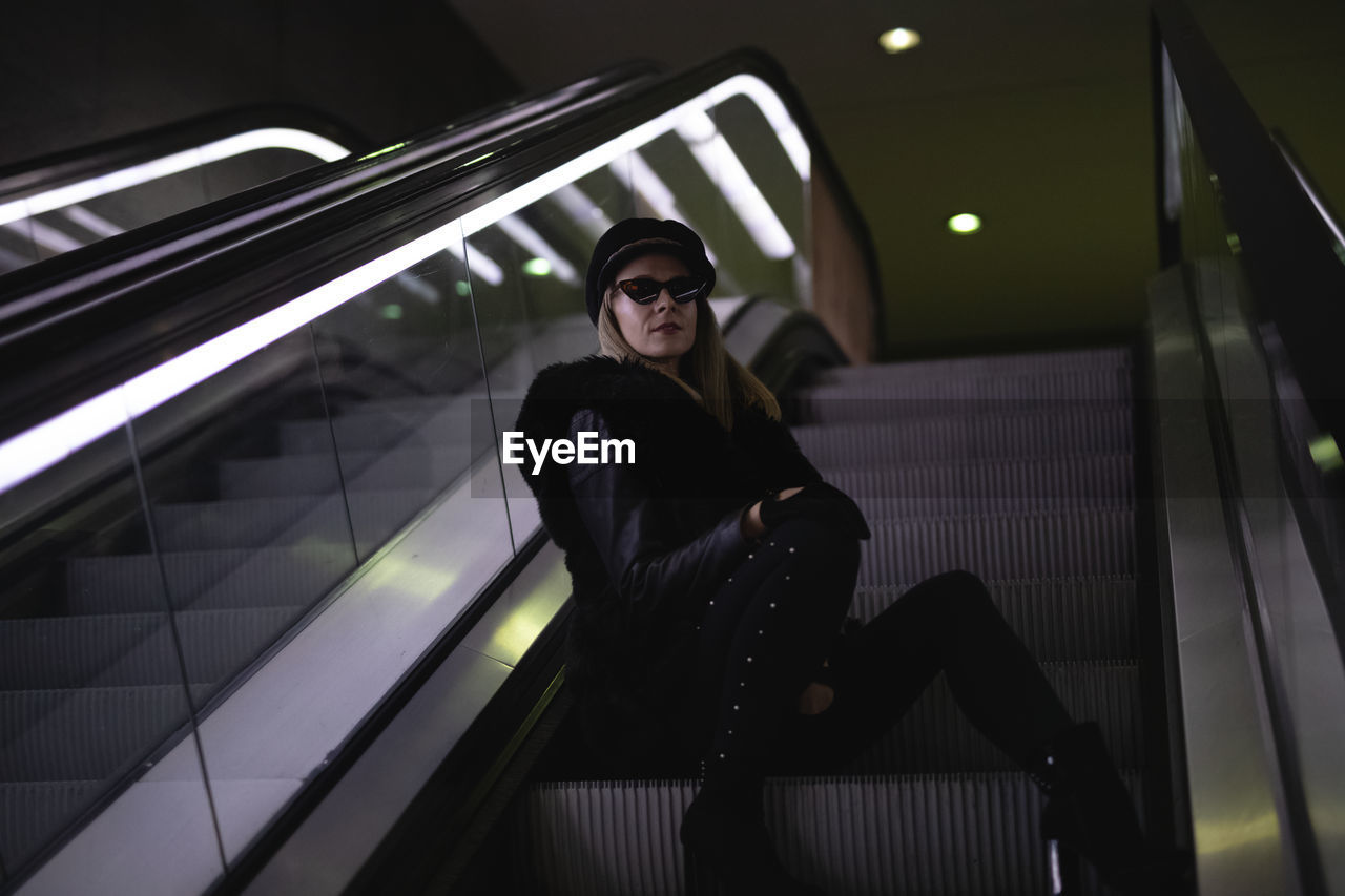 Portrait of woman sitting on escalator