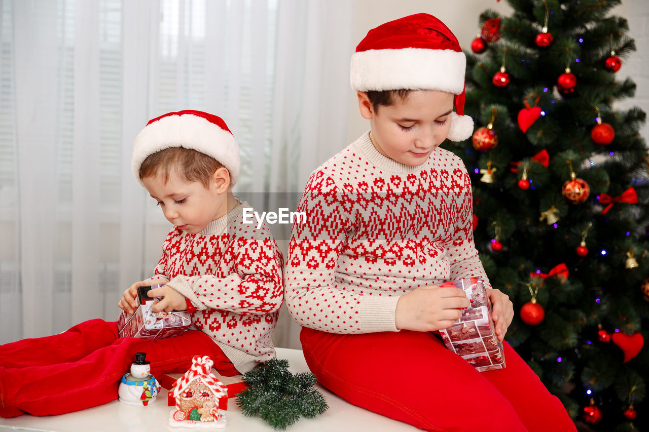 Surprised children unpack christmas gift boxes. smiling boys
